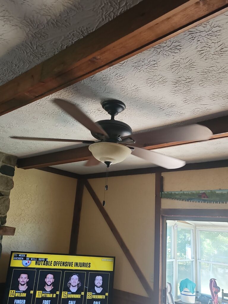 Ceiling fan installed between exposed wood beams in a Tudor-style room by Browning Craftsman Services