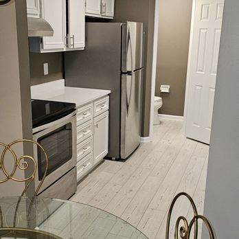 Finished compact kitchen by Browning Craftsman Services, with white cabinets, stainless appliances, and a light wood-look floor