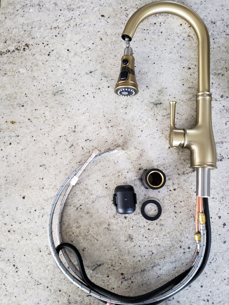 New brushed-gold pull-down kitchen faucet with supply lines and parts laid out on a granite countertop before installation by Browning Craftsman Services